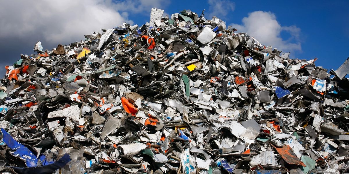 A large pile of crushed metal scrap under a blue sky.